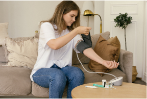 A woman checking her blood pressure sitting on sofa