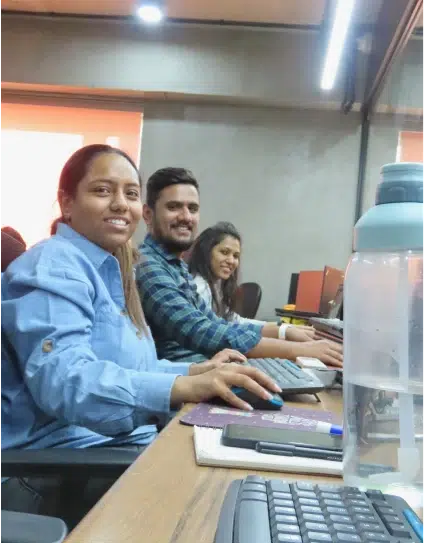 Team members of UX Team sitting at the desk and looking at camera